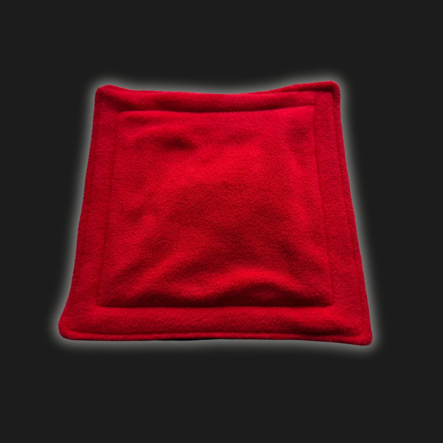 Enchantingly vibrant red modular fleece liner and matching pee pad, both cloaked in plush, gothic-soft fleece with neatly stitched edges, rest dramatically against a midnight-black backdrop. This cozy accessory set is perfect for pampered guinea pigs and other tiny familiars seeking comfort in style—witchy warmth meets whimsical charm!.
