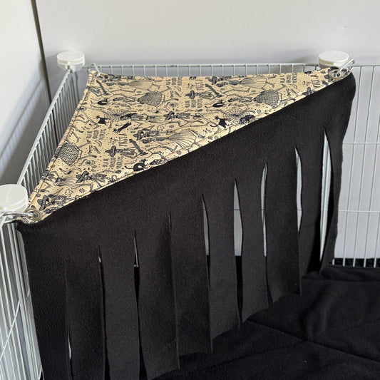 The Tombstone Tango Corner Fleece Forest transforms any cage corner into a haunted hideaway for your small pet—draped in enchanting black fringe that sways like midnight shadows, with a gothic tombstone-patterned canopy overhead. Whimsical yet cozy, this plush fleece retreat invites guinea pigs and little creatures to lounge in mysterious comfort and playful style.