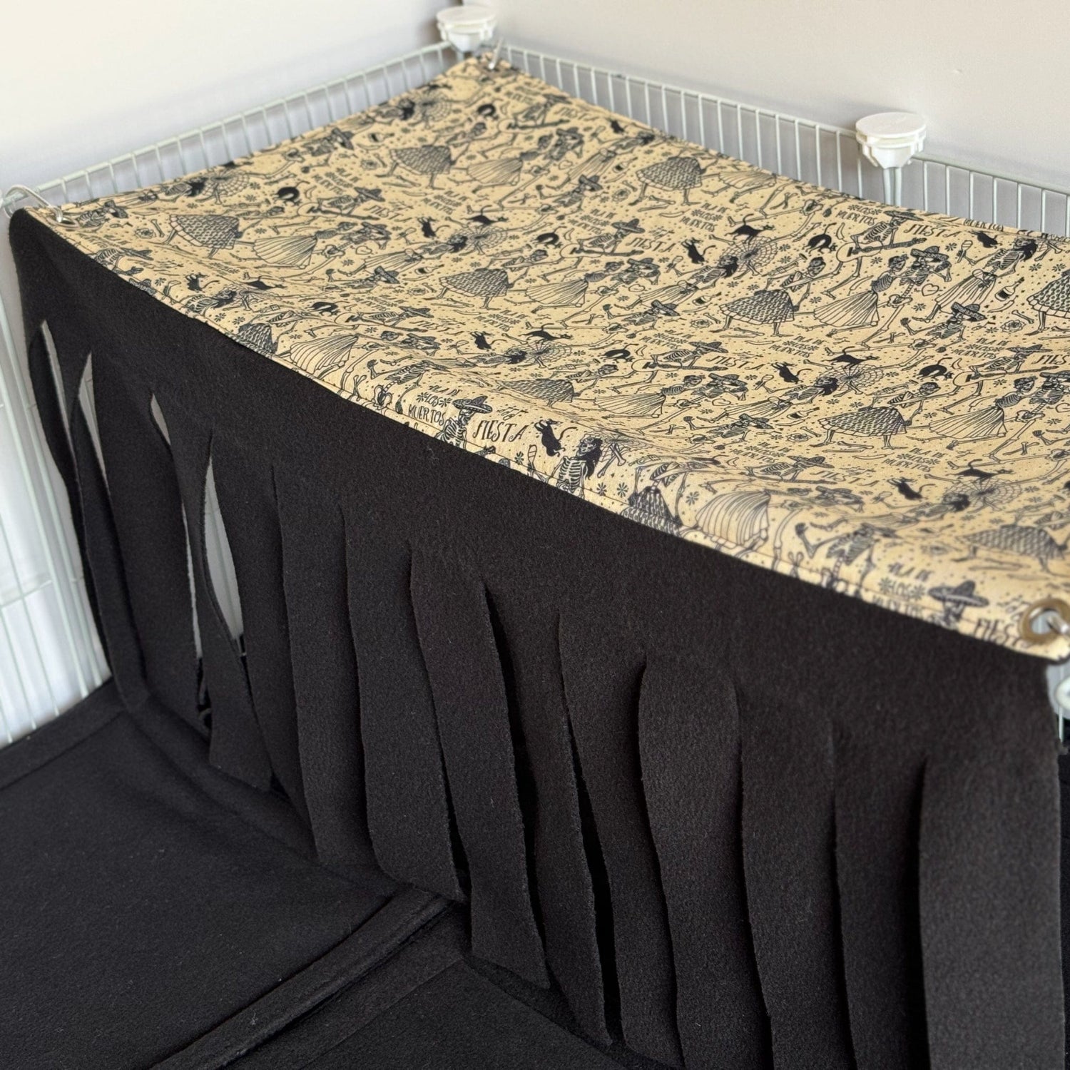 Step into the mystical midnight waltz with our Tombstone Tango Large 2x1 Fleece Forest—a bewitching Día de los Muertos-inspired hideaway for your piggies! Features a gothic-chic black and tan illustrated pattern of whimsically carved tombstones and sugar skulls, with plush fleece strips cascading like enchanted curtains to create a cozy, shadowy nook perfect for spooky-cute snuggles in their cage.