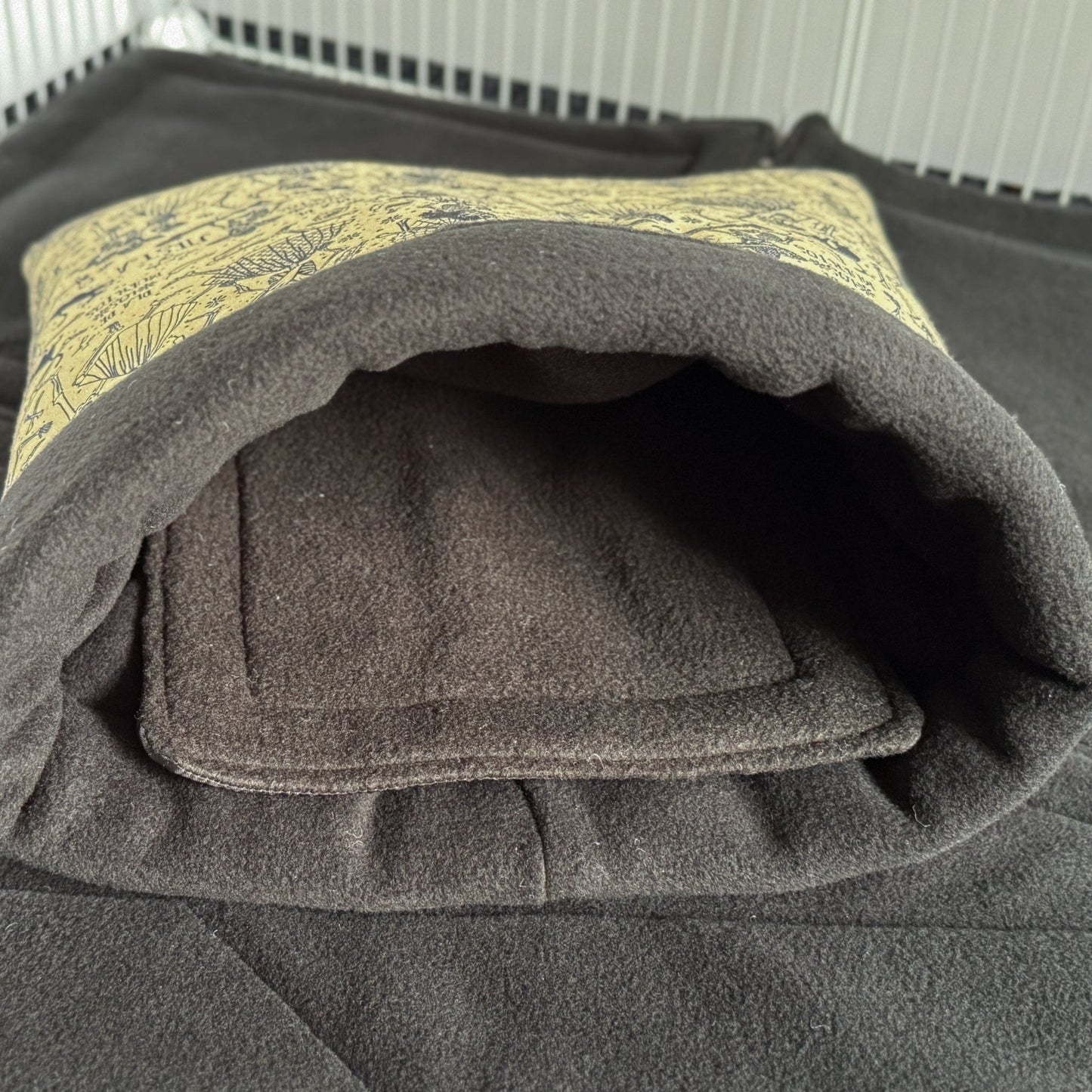 The Tombstone Tango Snuggle Sack—a bewitchingly cozy tunnel in shadowy charcoal gray, edged with a pop of moonbeam-yellow trim—rests waiting on a matching gothic playmat. Its plush fleece lining beckons tiny creatures of the night (and nap!) to slip inside for warmth, security, and cuddles fit for the cutest ghouls. Perfect hideaway for guinea pigs or any small pet with an enchanting flair.