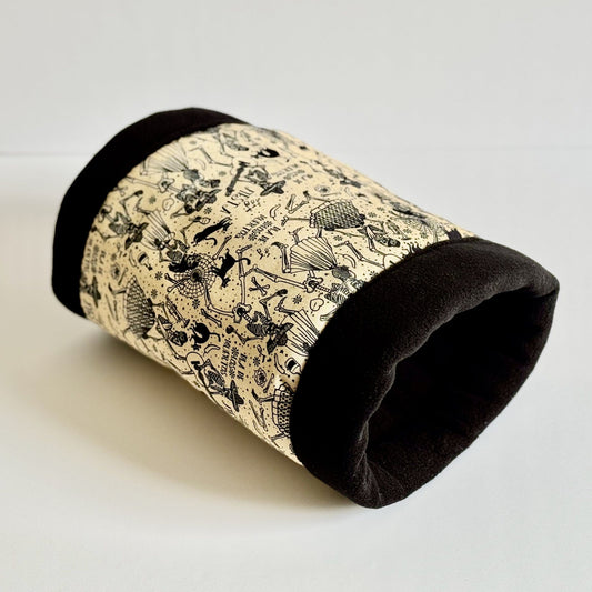 The Blooms & Bones Fleece Tunnel is an enchanting, cozy tunnel for guinea pigs and small pets. Its plush black fleece ends evoke the elegance of midnight velvet, while the beige center beguiles with a whimsical parade of black gothic-style animals and mysterious motifs—think bats, bones, blooming flowers, and playful critters. Resting atop a moonlit white backdrop, this snuggly hideaway conjures both spooky delights and cuddly comforts for your magical little companion.