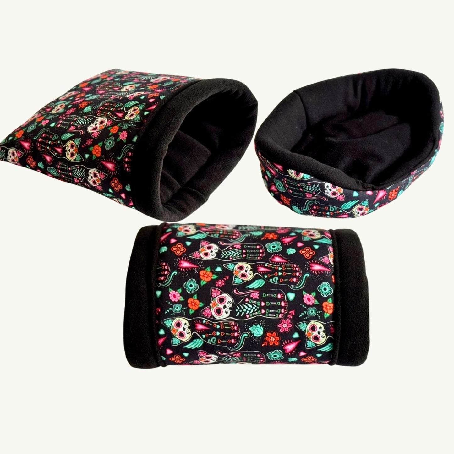 Three cozy pet beds and tunnels enchant in gothic black with vibrant sugar skulls and blooms—spooky-cute snuggle trio on white.