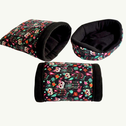 Three cozy pet beds and tunnels enchant in gothic black with vibrant sugar skulls and blooms—spooky-cute snuggle trio on white.