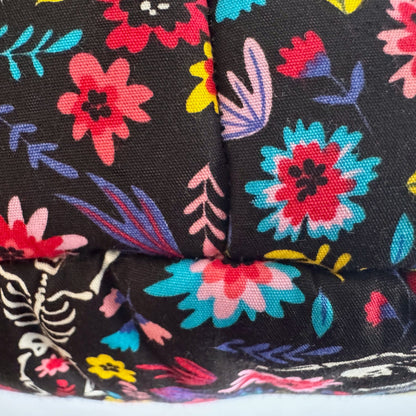 Spooky-cute close-up of our Blooms & Bones Fleece Bed fabric: dramatic black fleece adorned with enchanting bursts of magenta, violet, and crimson blooms, weaving through a mysterious partial white skeleton. Perfectly plush for pampered guinea pigs or other petite familiars seeking cozy gothic-glam slumber!.
