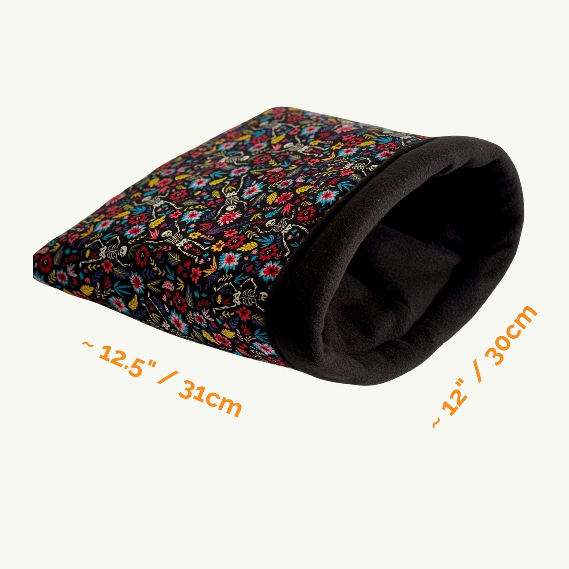 The Blooms & Bones Snuggle Sack—a bewitching blend of midnight florals and mystical bone motifs—offers your darling guinea pig or small pet a luxuriously soft fleece hideaway. This gothic-glam tunnel, draped in vibrant blossoms upon an enchanting dark background, measures approximately 12.5 inches by 12 inches. Perfect as a charmingly eerie cuddle nook, shown invitingly against a pale, moonlit backdrop.