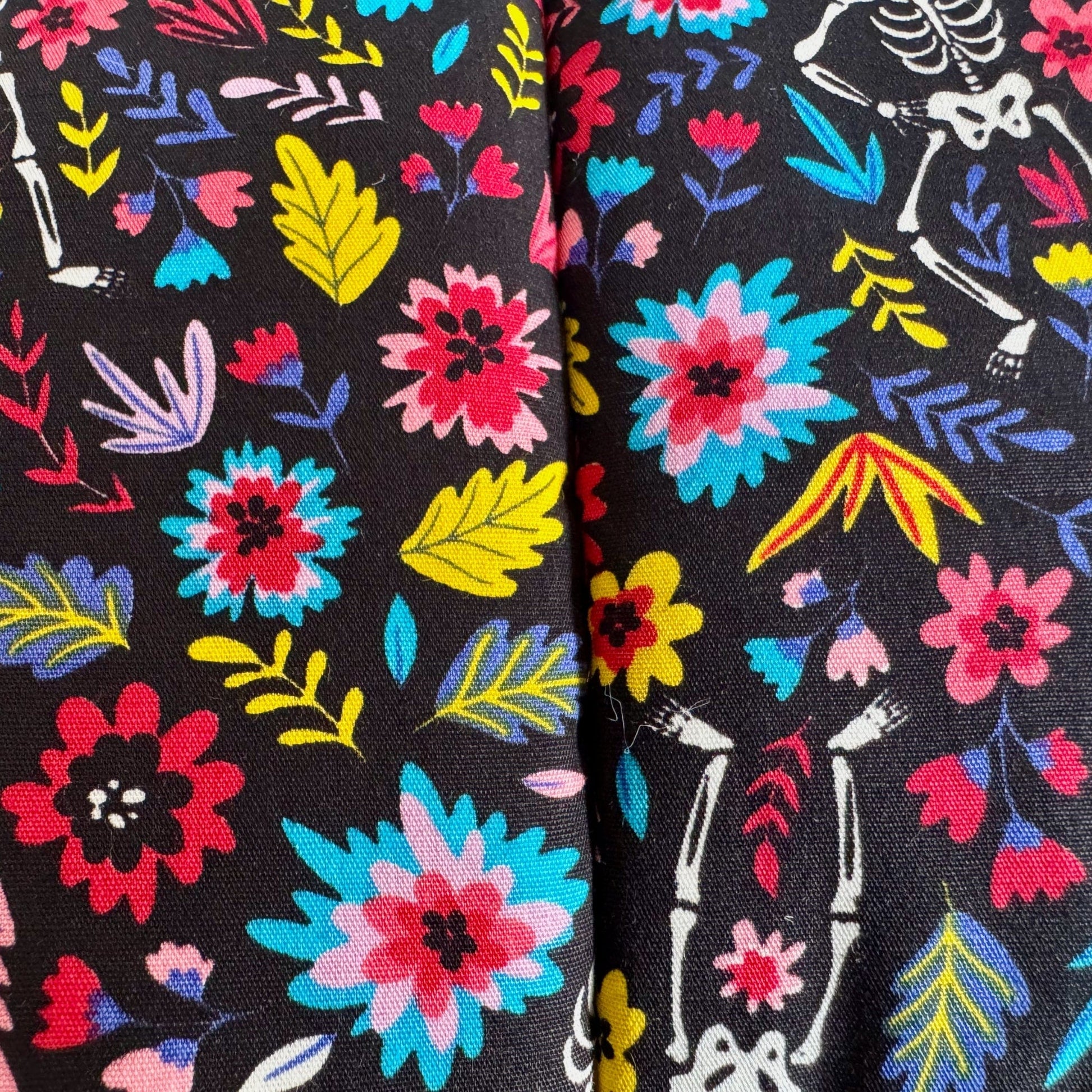 The Blooms & Bones Snuggle Sack enchants with inky black fabric, swirling with bright, bewitching florals and leaves. Ghostly white skeleton shapes peek playfully between the petals, conjuring a gothic-glam vibe. Inside, a plush fleece lining invites your small pet to burrow in comfort—perfect for snuggly guinea pigs or other tiny familiars seeking cozy gothic charm.