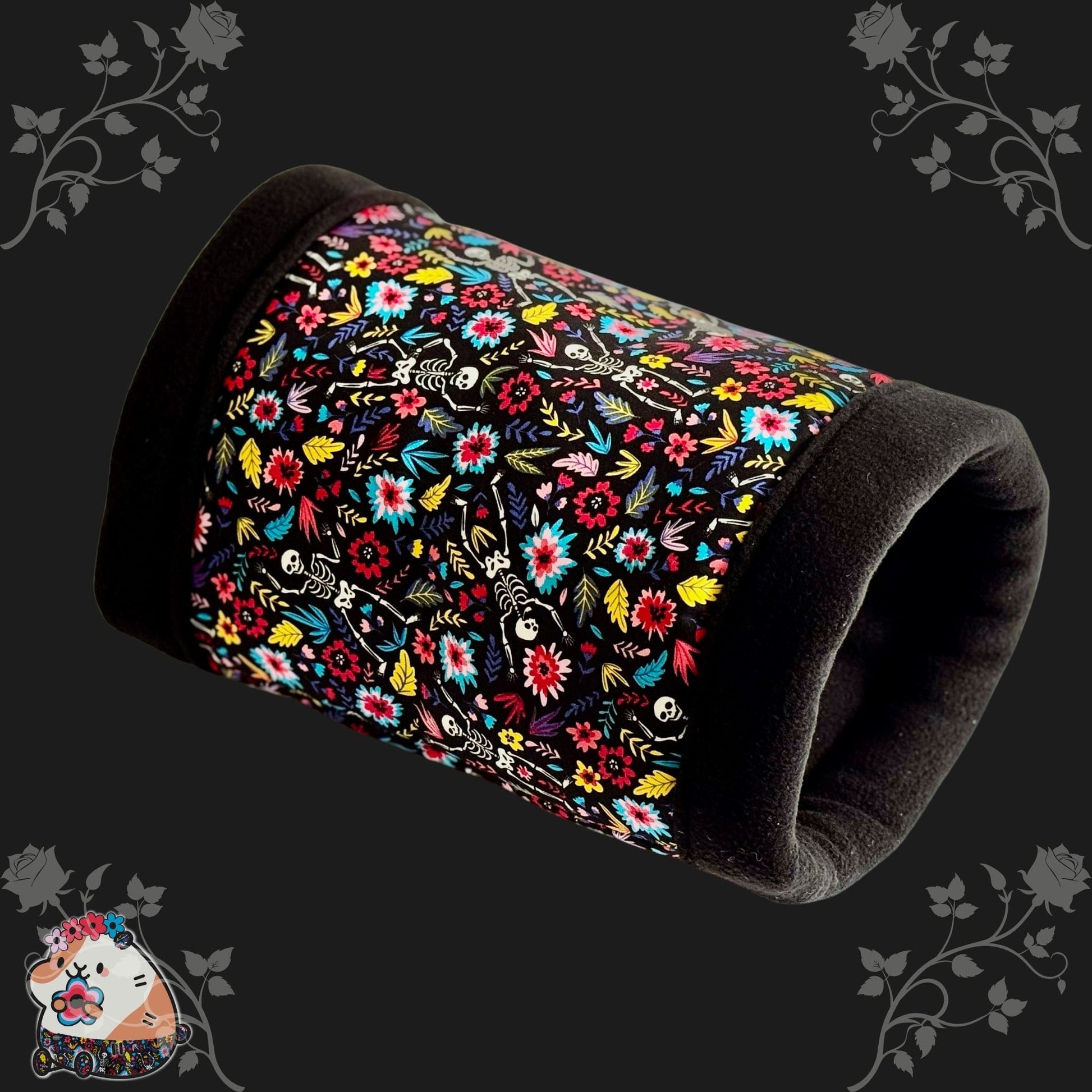 The Blooms & Bones Fleece Tunnel is a cozy, cylindrical hideaway for guinea pigs and small pets, bedecked in gothic-glam style. Black trim edges midnight-black fleece adorned with whimsical white skeletons entwined with moody floral vines. Set against a shadowy background bordered by dark, enchanted blossoms, a charming cartoon guinea pig peeks out from the corner—ready for spooky-cute snuggles in this mysterious little lair.