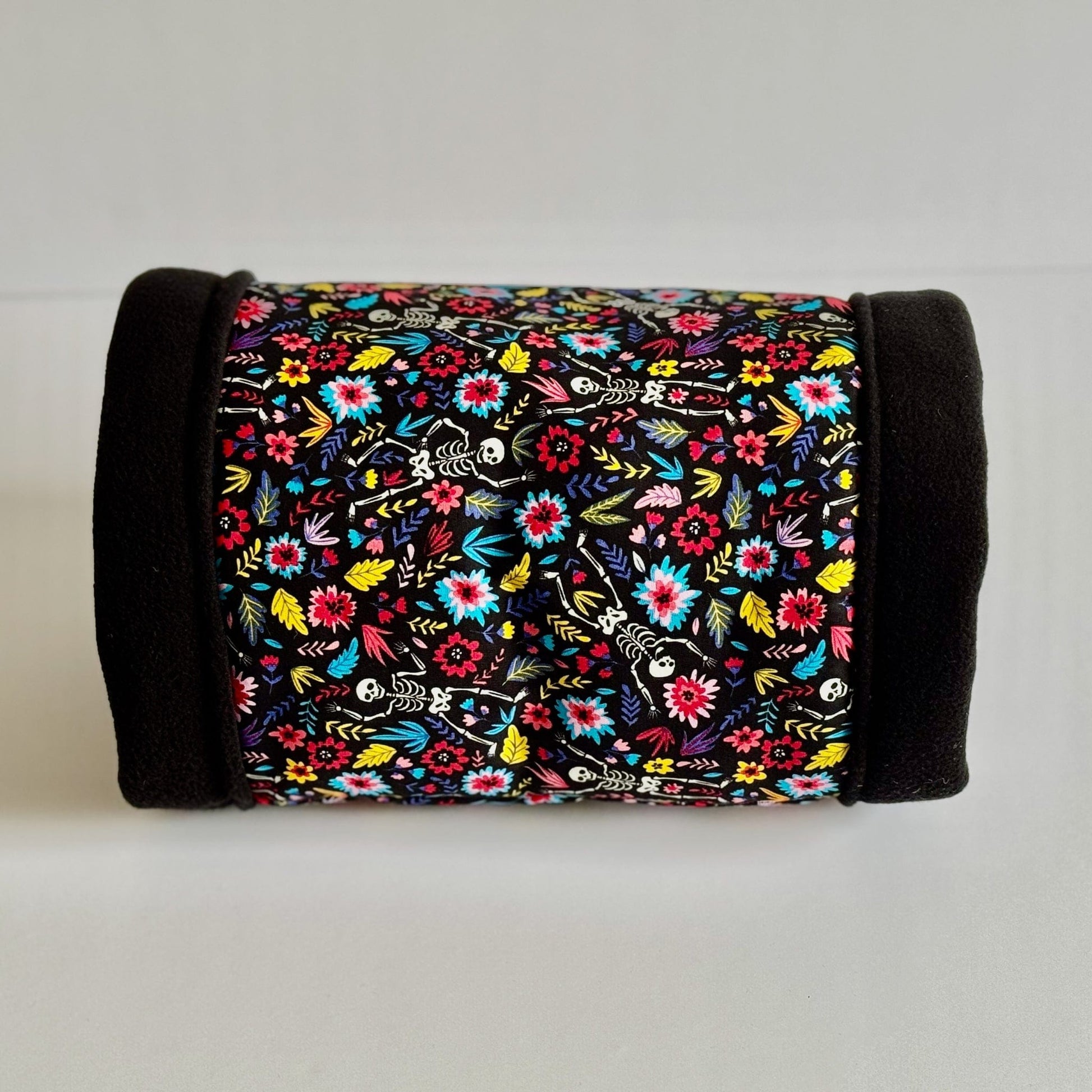 The Blooms & Bones Fleece Tunnel awaits, cloaked in midnight-black fleece ends and enchanted with a vibrant bouquet of gothic florals entwined with playful ivory skeletons. This cozy tunnel, perfectly sized for guinea pigs or small animal familiars, offers a haunt of spooky-cute comfort—displayed here against a crisp white background, ready to charm your beloved pet.