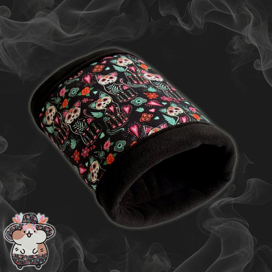 The Curious Catrina Fleece Tunnel enchants with gothic-glam flair—a plush black tunnel for guinea pigs, adorned in lively sugar skull cats and whimsical blossoms swirling across a dusky, smoky backdrop. A tiny illustrated mouse peeks playfully from the bottom left corner, adding a dash of adorable mischief for your spooky-cute companion.