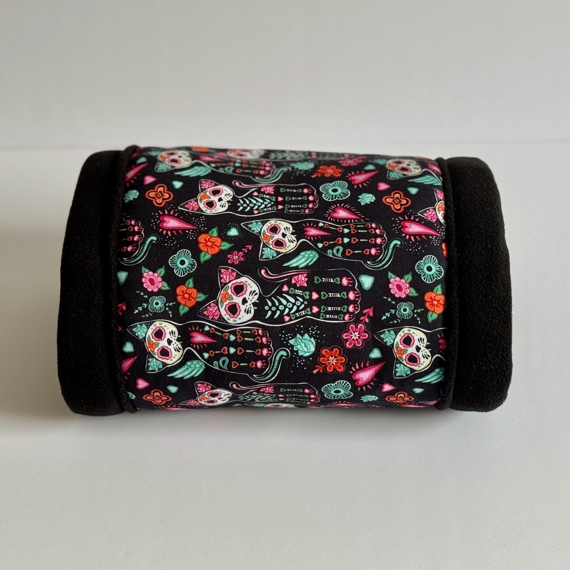 The Curious Catrina Fleece Tunnel beckons your beloved small pet into a world of gothic charm—a cozy, cylindrical hideaway trimmed in midnight-black fleece. Its enchanting fabric is adorned with whimsical sugar skull kitties, vibrant flowers, and twining leaves that glow against an inky backdrop. A spooktacular sanctuary for adventurous guinea pigs or spirited small animals seeking snuggly glamour!.