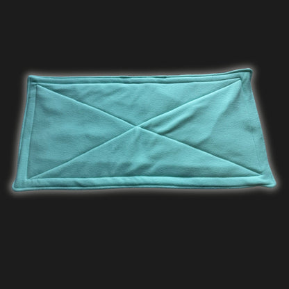 Bewitchingly mint green rectangular fleece liner and matching pee pad, stitched with enchanting diagonal X patterns, lay in gothic elegance against a shadowy backdrop—perfectly plush for your wee familiars or guinea pig ghouls to nestle in supernatural comfort.