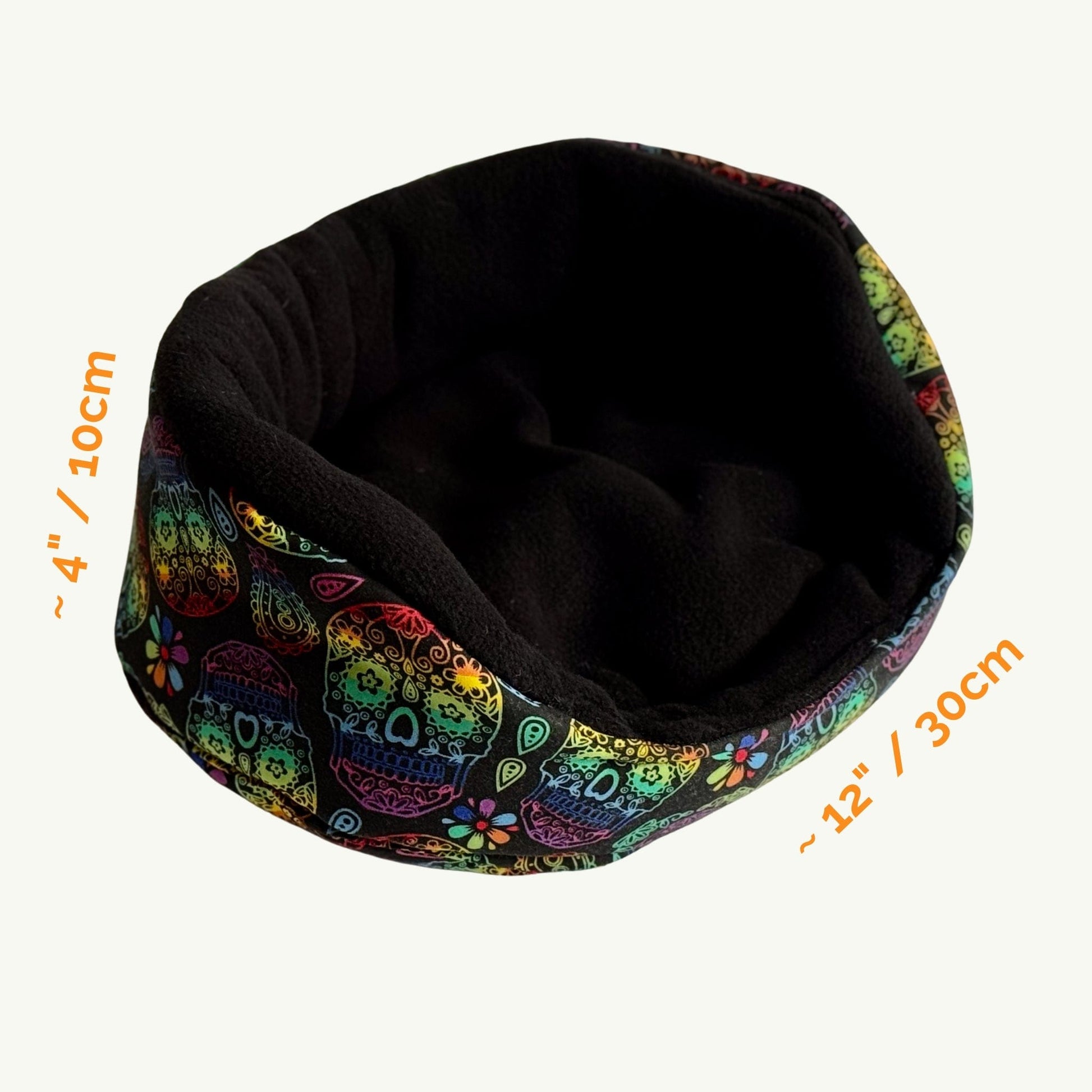 The Frightful Fiesta Fleece Bed enchants with a gothic-glam twist—its outer fabric is bedecked in vibrant, whimsical sugar skulls and fluttering florals, exuding spooky-cute vibes. The cozy interior wraps small pets in plush midnight-black fleece, perfect for stylish guinea pig naps. Bed measures approximately 4 inches (10 cm) tall and 12 inches (30 cm) wide.
