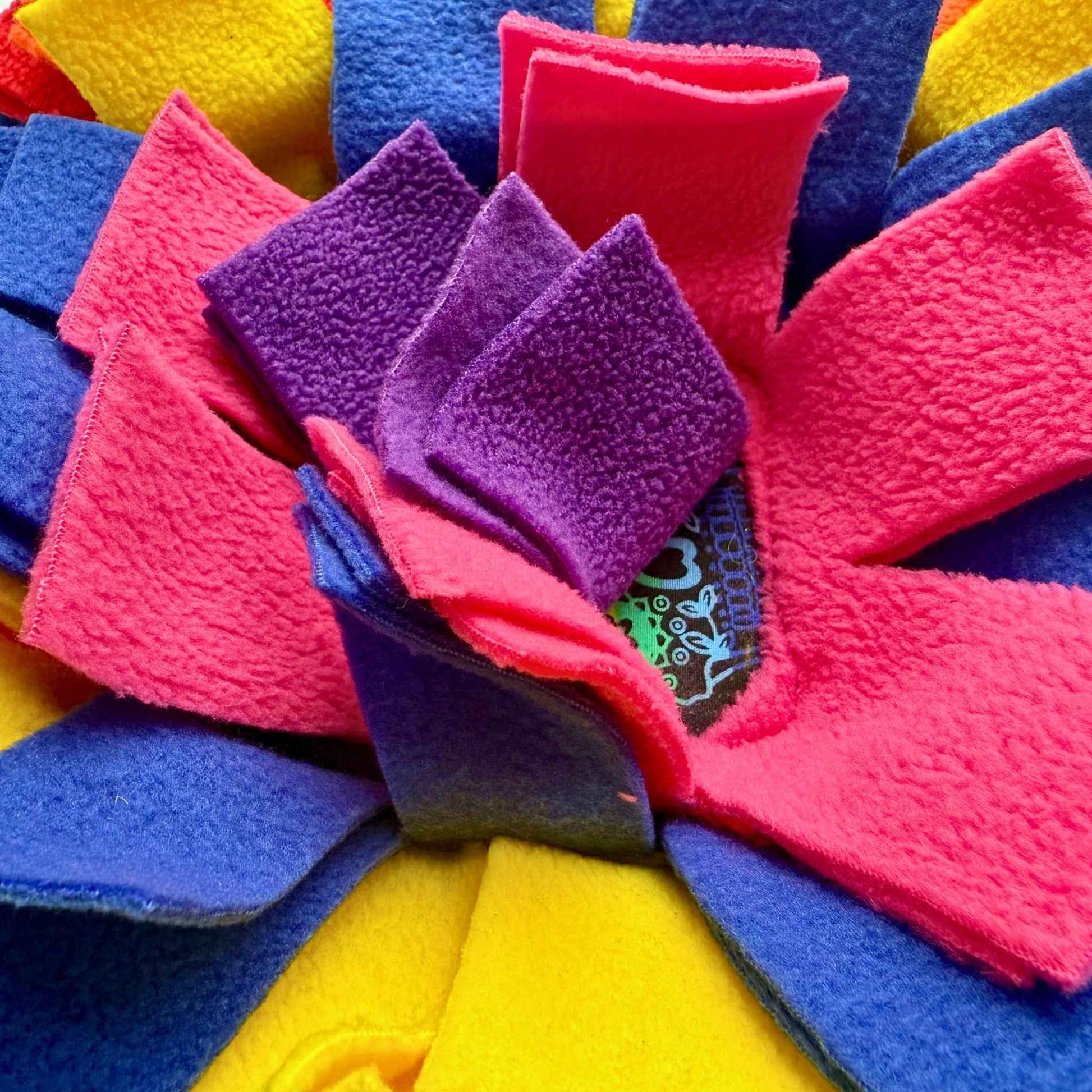 Glimpse neon pink, purple, blue, and yellow fleece strips swirling on the Frightful Fiesta Snuffle Mat—centered by a gothic tag.