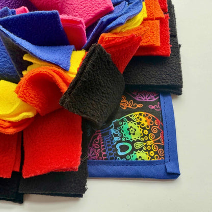 A dreamy pile of yellow, red, pink, blue, and black fleece haunts beside sugar skulls—perfect for a spooky-snuggly snuffle mat.