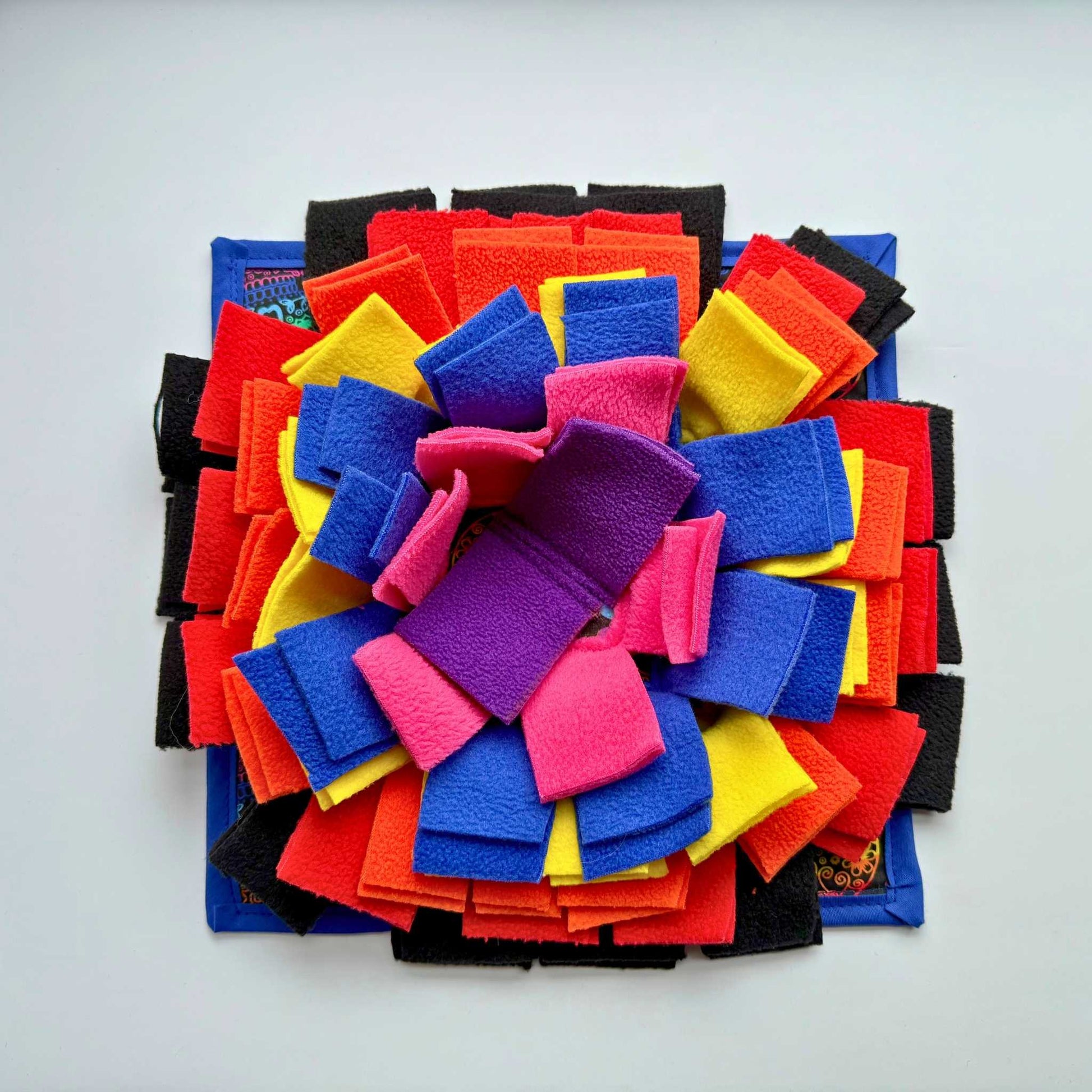 The Frightful Fiesta Snuffle Mat casts a spell with jewel-toned felt petals on white, making guinea pig snack hunts enchantingly fun.