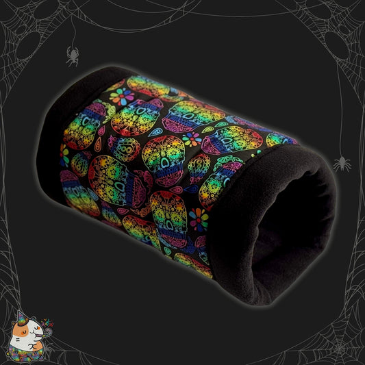 The Frightful Fiesta Fleece Tunnel is a cozy black hideaway for small pets, bedecked with vivid rainbow sugar skulls, twirling flowers, delicate spiderwebs spun with silver threads, and charming little spiders. A mischievous cartoon cat in gothic garb clutches a smiling pumpkin amid the vibrant fiesta pattern—perfect for guinea pigs or other tiny familiars to scamper through on spooky-cute adventures.