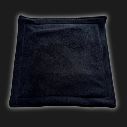 A bewitching black fleece liner and matching pee pad set, cut in a charming square with gently raised, coffin-chic edges. Perfectly plush for pint-sized familiars—ideal as a washable potty pad or cozy throne for your small pet ghoul.
