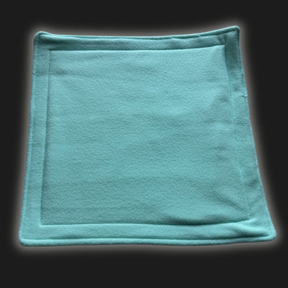 A bewitchingly soft, mint green fleece liner and matching pee pad—stitched with care and finished with delicate hems—lie spellbound atop a midnight-black backdrop. The cozy square set invites little familiars to nestle in gothic-glam comfort, perfect for pampered guinea pigs or charming small creatures. Washable magic keeps every enchanted nook fresh for your darling beasties.