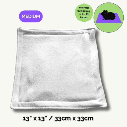 The Pee Pads | Turn daily cleanup into a spellbinding breeze—our ghostly-soft, square fleece pad (13 x 13/33cm x 33cm) summons gothic glam with its crisp white surface, vibrant purple MEDIUM label, and an enchanted green guinea pig illustration. Perfectly sized for your darling familiars (average guinea pigs, 8–10 inches), this pad brings a dash of whimsical charm and moonlit magic to every cozy corner.
