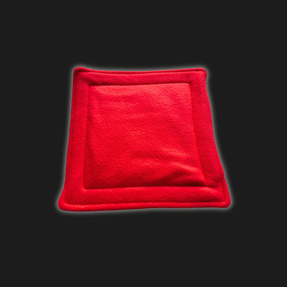 A bewitchingly cozy, blood-red fleece liner and matching petite pee pad for small pets—plush squares edged in gentle piping, like a velvet cushion fit for gothic royalty. Resting atop a mysterious black backdrop, this handmade accessory is delightfully soft, shimmery with gentle luster, and promises snug comfort with an enchanting touch—perfect for guinea pigs and tiny familiars craving comfort in style. Washable and practical magic woven into every stitch!.