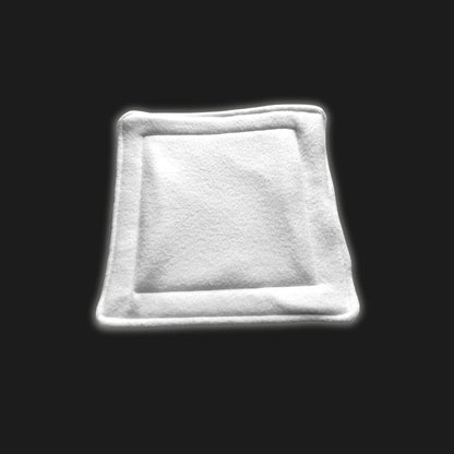A ghostly-white modular fleece liner and matching pee pad rest enchantingly on a pitch-black stage, their plush, velvety texture evoking moonlit comfort for tiny familiars. Sized just right for pampered guinea pigs or enchanting small pets, this washable set promises mystical coziness and easy clean-up—perfect for gothic-glam cages in need of a touch of whimsy.