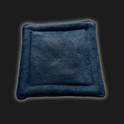 A bewitching black fleece liner and matching pee pad, crafted for small pets, haunt the center of a shadowy backdrop. Their plush, velvety texture shimmers with eerie softness, ruby stitches twinkling like gothic jewels. The set glows gently at the edges—summoning cozy comfort for your pets midnight adventures.