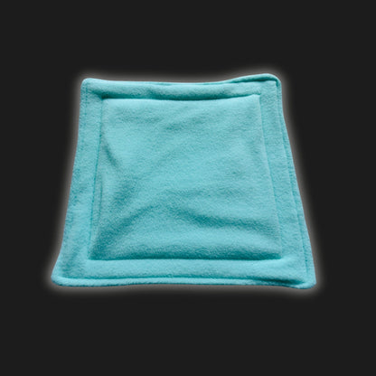 Enchant your little familiars with this bewitching rectangular fleece liner and matching pee pad, both in a hauntingly soft mint green, their edges elegantly stitched like a patchwork spell. Nestled against an inky black backdrop, this cozy sanctuary promises washable witchery—just right for pampered guinea pigs and mysterious critters who love cuddly comfort with a gothic twist.