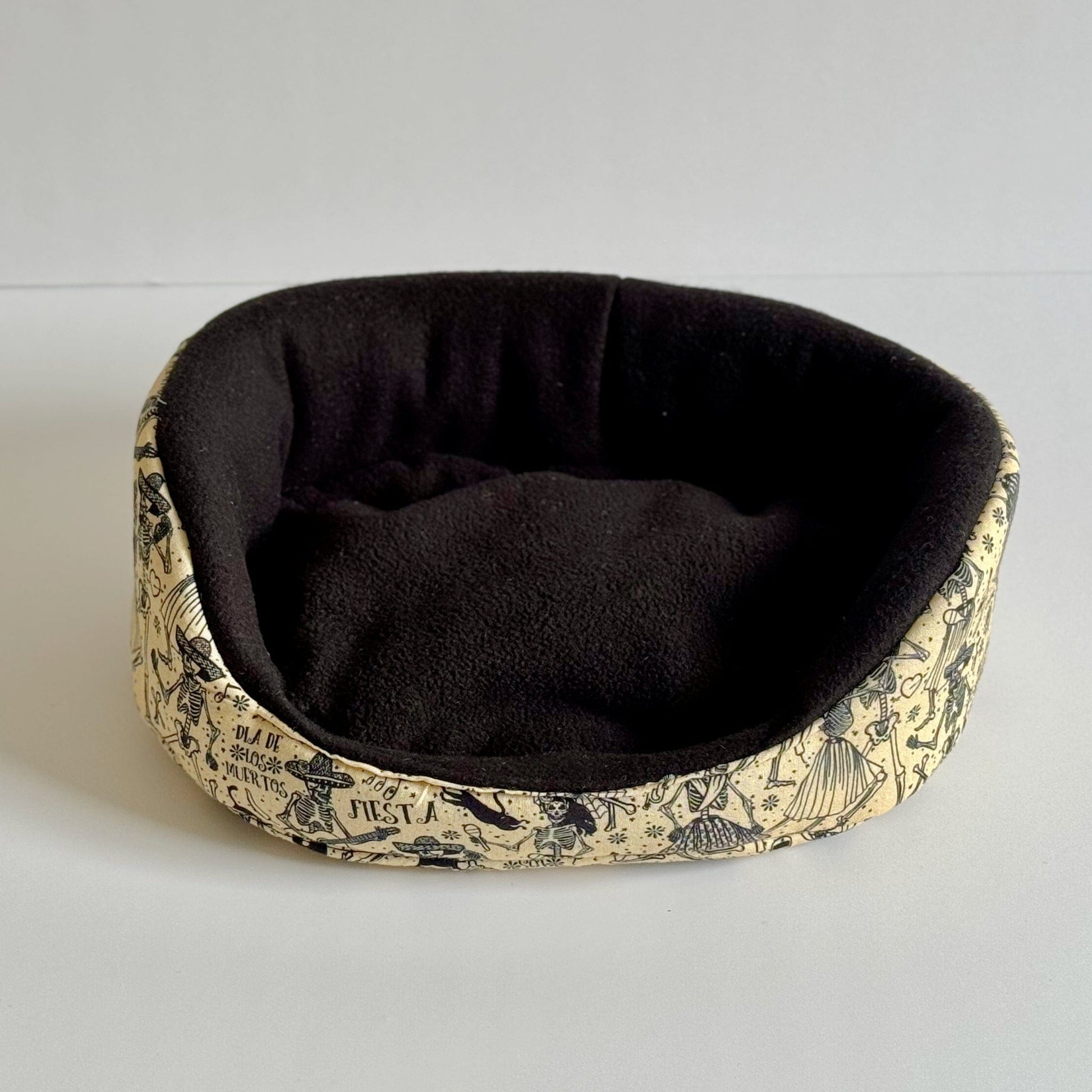 The Tombstone Tango Fleece Bed beckons your little ghoul with a plush black velvet lining and coffin-beige sides, bewitched by charming black mushrooms and gothic botanicals. This rectangular nest of cozy enchantment invites guinea pigs and small creatures to snuggle in midnight comfort. Displayed on a pale, spectral backdrop for fang-tastic detail.
