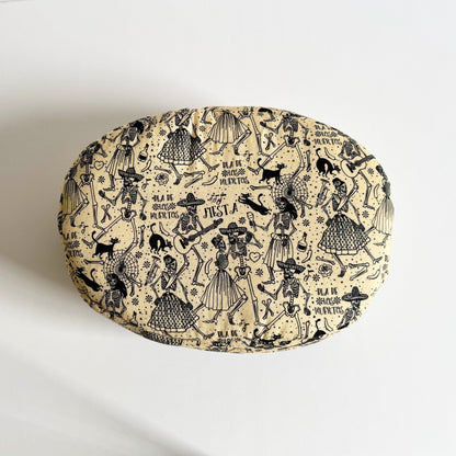 The Tombstone Tango Fleece Bed is a plush, round cushion—its creamy beige fabric bewitched with inky-black sketches of skeleton dancers and fanciful musicians swirling across the surface. Playful gothic script proclaims “Viva la Vida” among festive skulls, roses, and swirling bats. A haunt-fully cozy nest for guinea pigs or other small companions to curl up in style, blending supernatural charm with snug comfort.