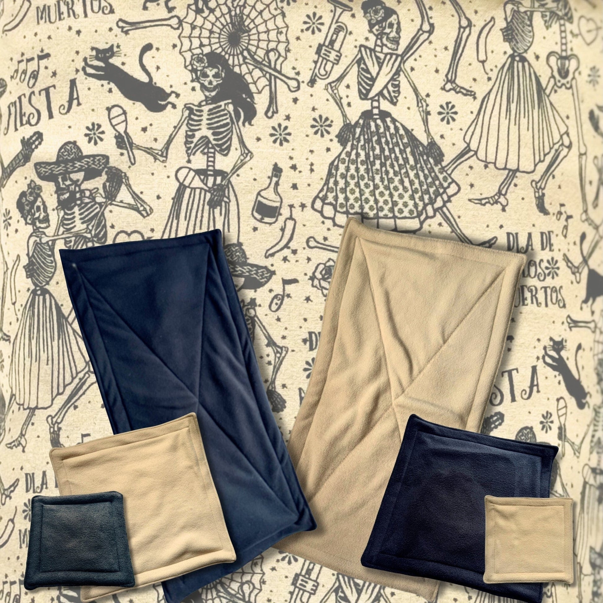 Three enchanting sets of navy blue and beige blankets and pillows lie atop Tombstone Tango Pee Pads—spine-chillingly cute bedding for small pets. Each absorbent pad is cloaked in Día de los Muertos magic, bursting with playful dancing skeletons, marigold petals, and swirling festive patterns. Perfect for guinea pigs or other tiny familiars who dream of gothic-glam coziness with a dash of ghostly whimsy!.