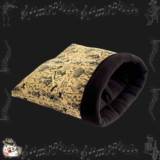 The Tombstone Tango Snuggle Sack is a bewitchingly cozy tunnel for guinea pigs and small pets, stitched from antique-inspired beige cotton patterned with whimsical black skeletons mid-dance and floating music notes. Finished with a plush black fleece lining for gothic glam comfort, this snuggle sack invites your little familiar to curl up in soft, spooky elegance—perfect for paranormal naps or midnight cuddles.