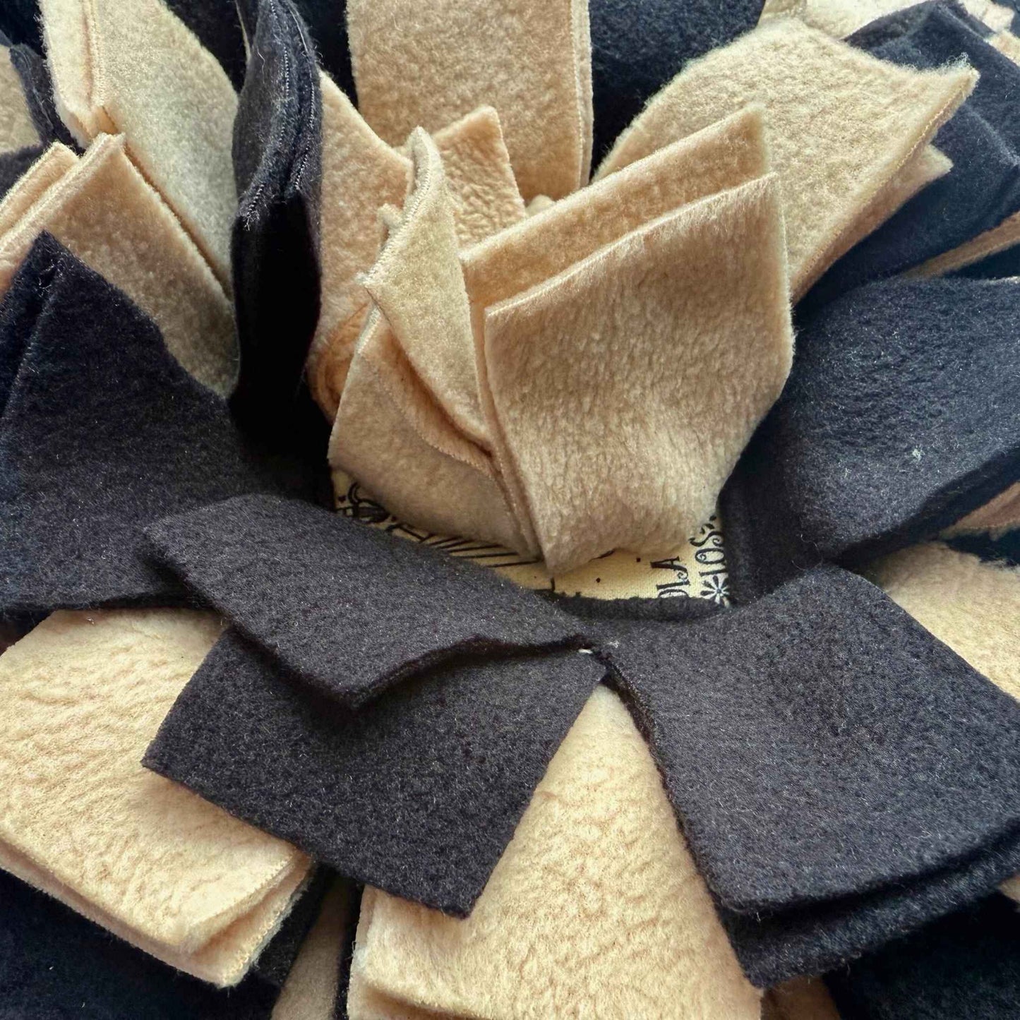 Enchanting close-up of the Tombstone Tango Snuffle Mat with ruffled black and beige fleece strips—where treats haunt velvet shadows.