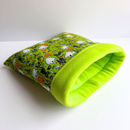 The Trickster’s Treats Snuggle Sack: a cozy tunnel of lime fleece, bedecked in gothic-cute monsters and Halloween whimsy for your piggy.