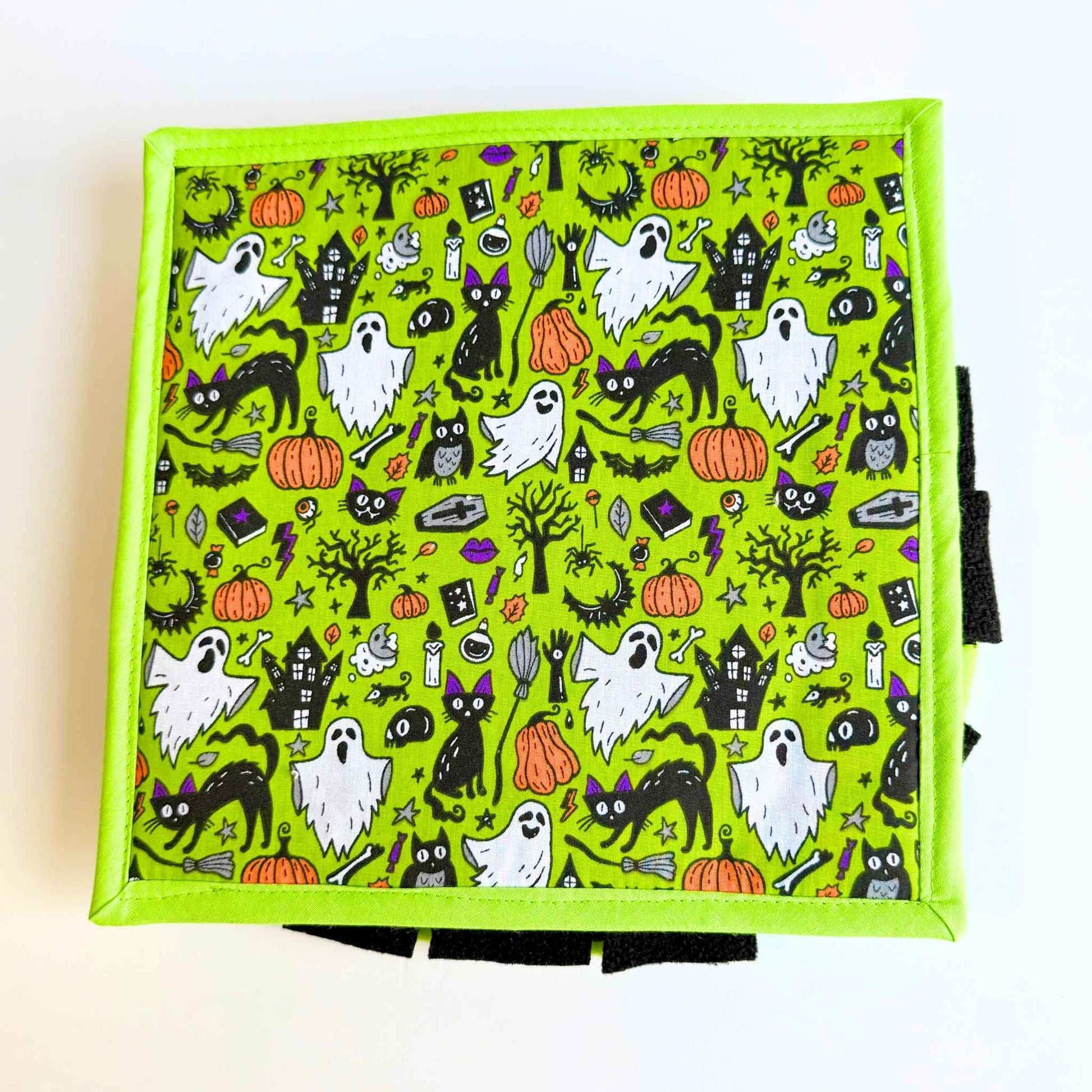 A square, vivid green snuffle mat bedecked with darling ghosts, cats, bats, pumpkins, and trees—spooky-cute treat time magic!.