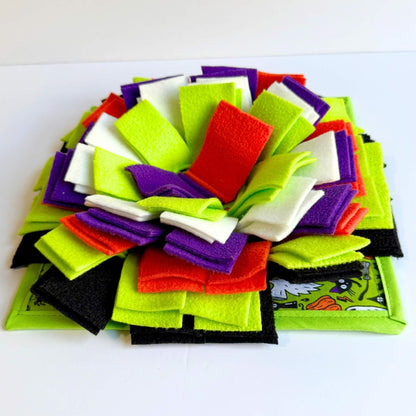 The Trickster's Treats Snuffle Mat flaunts a gothic bow in neon green, purple, and black atop a cartoon base—spooky-cute for piggies.