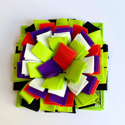 The Trickster’s Treats Snuffle Mat blooms in gothic-glam hues—petals of green, blood-red, purple, black, and haunting white fleece.
